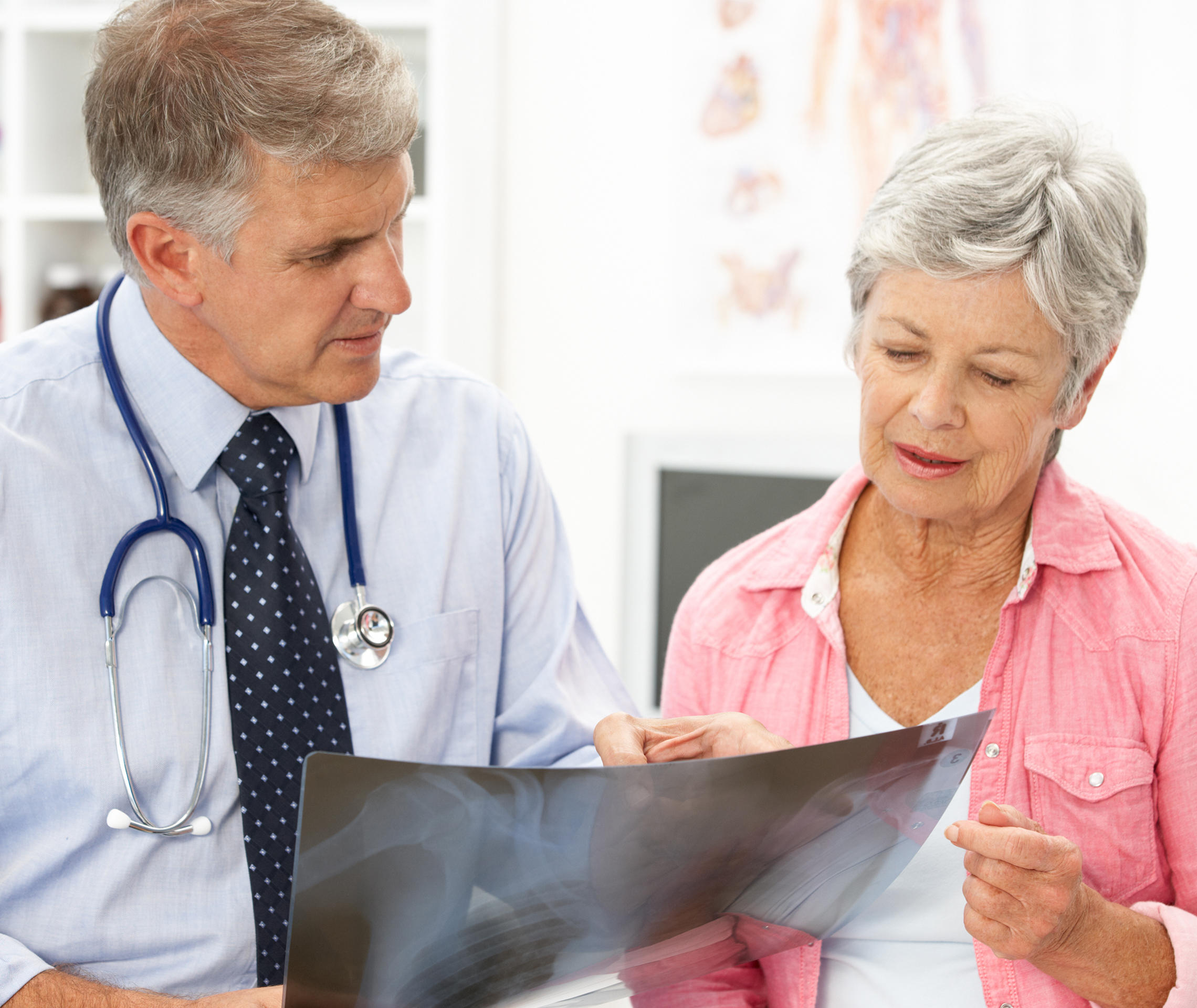 Ein Arzt hält eine Röntgen-Thorax-Aufnahme in der Hand und bespricht diese mit einer Patientin.