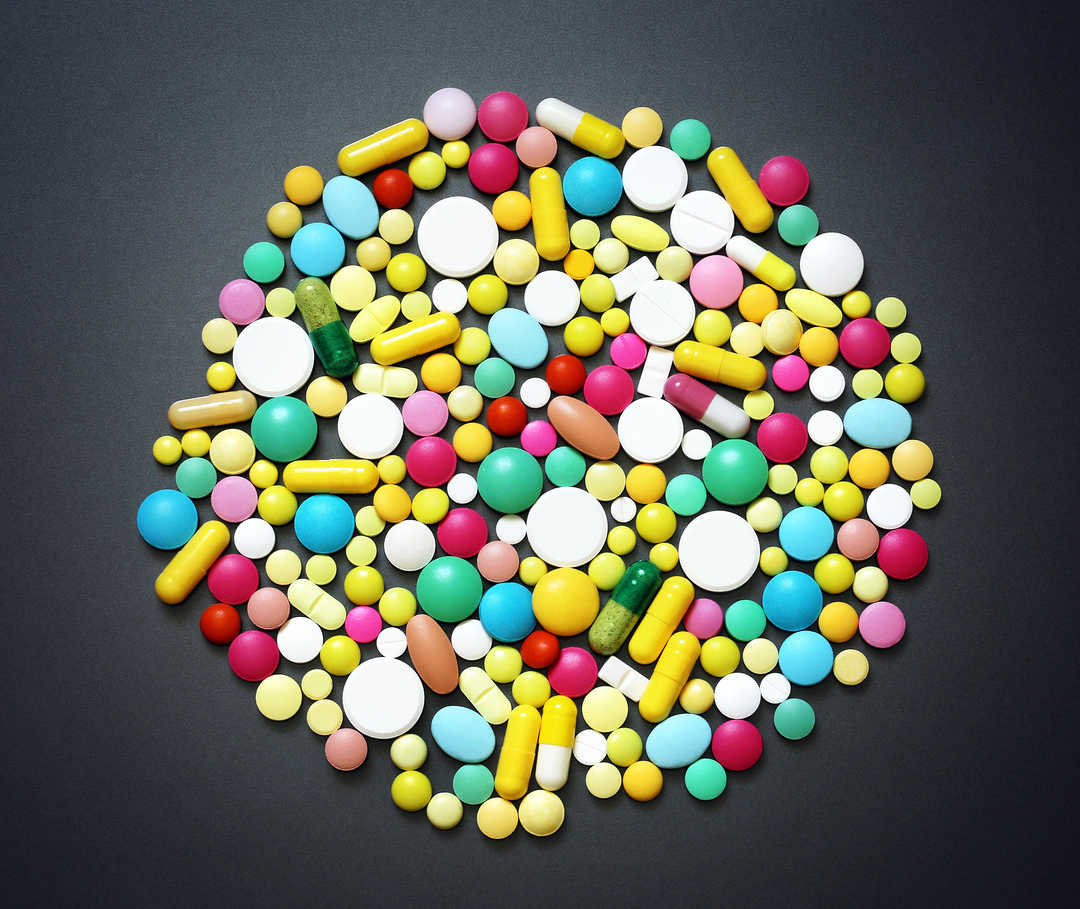 Verschiedene bunte Tabletten liegen auf einem Boden zu einem Kreis geformt.