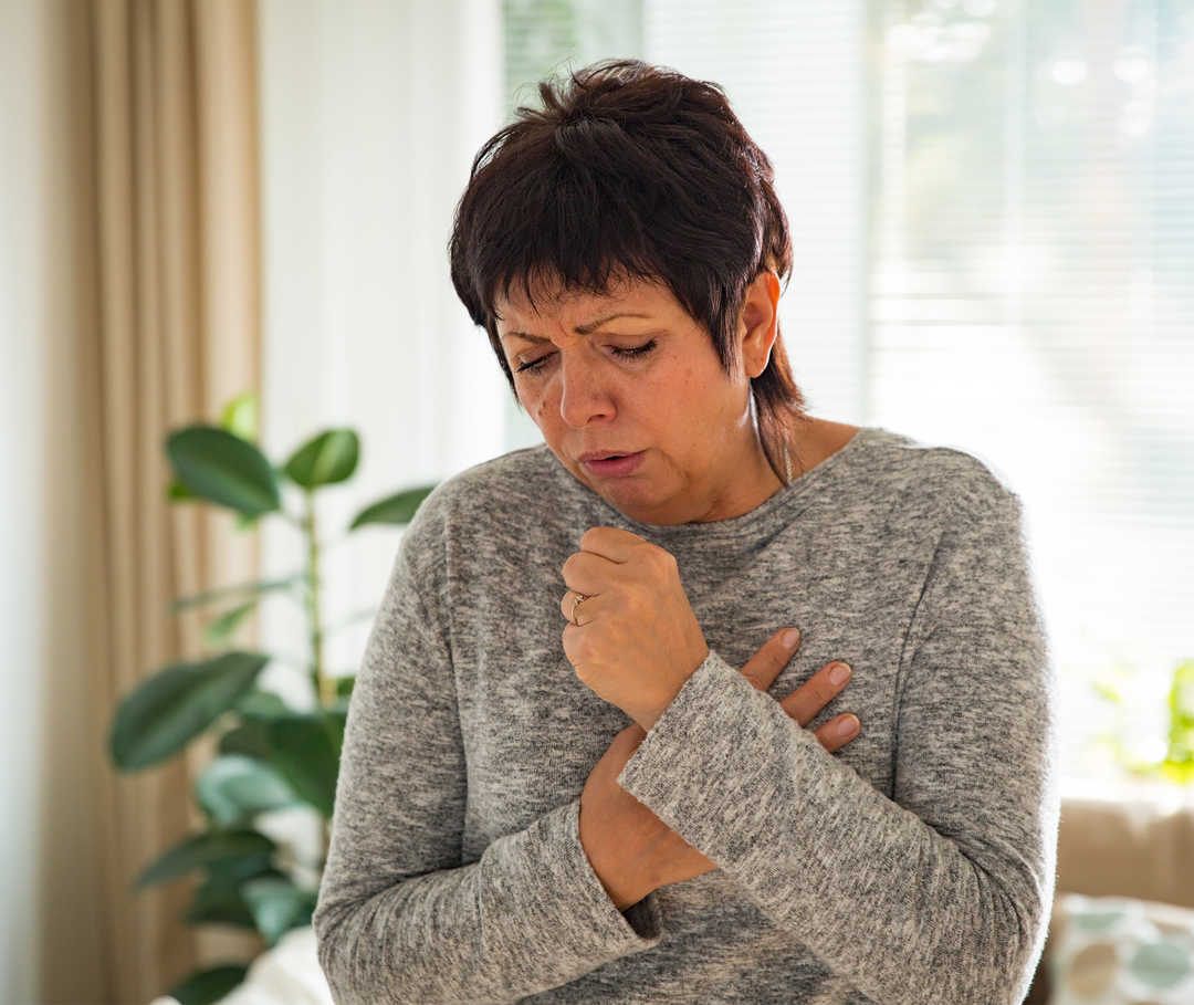 Frau mit Asthma cardiale hustet.