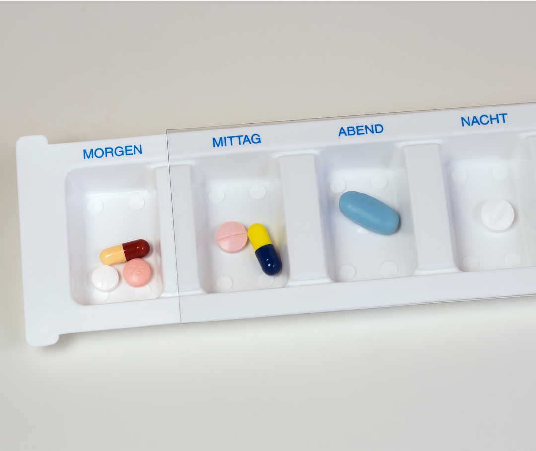 Medikamentenbox enthält Betablocker und andere Tabletten, die in einzelne Fächer für morgens, mittags, abends und nachts unterteilt sind.
