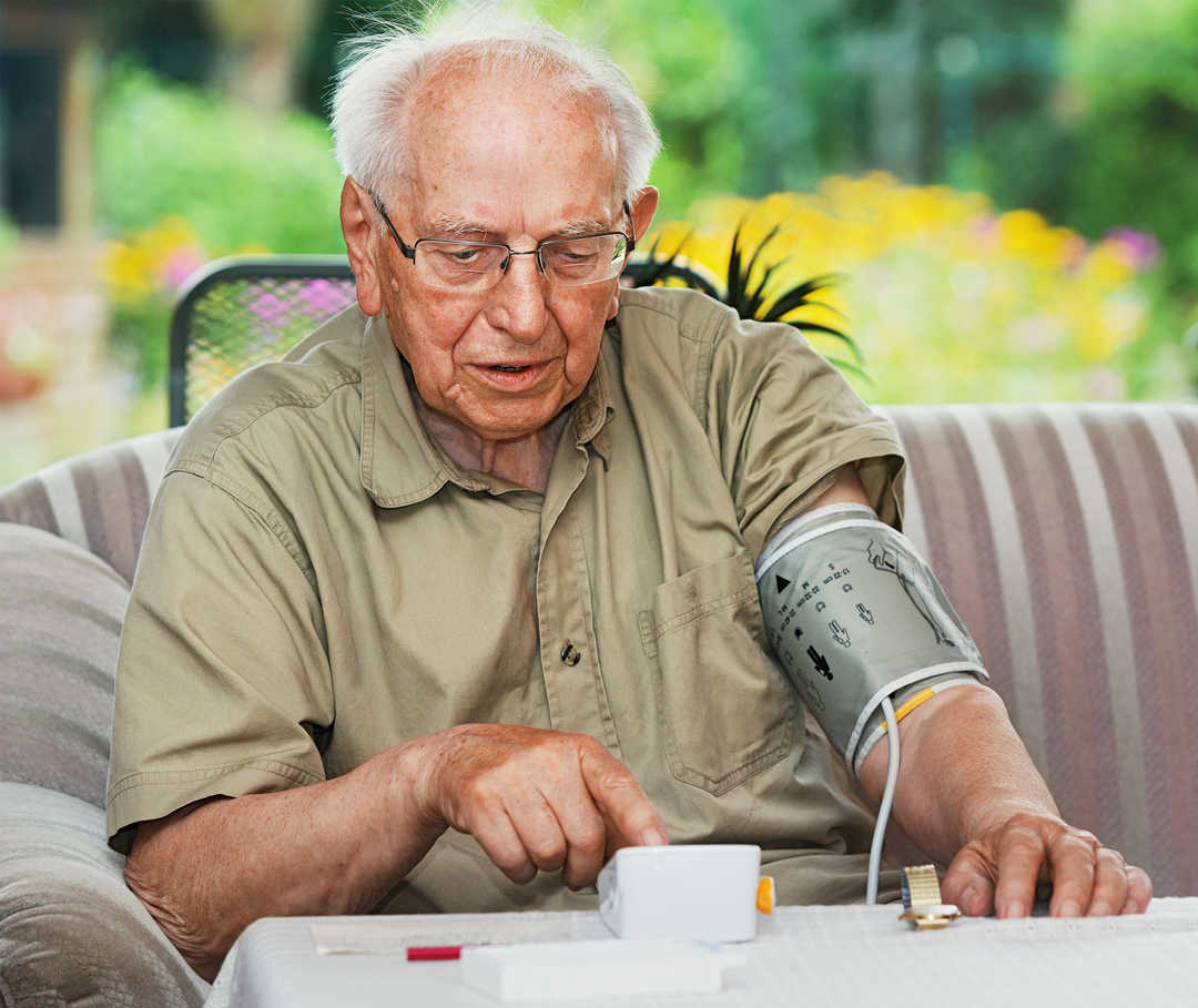 Bluthochdruckpatient kontrolliert mithilfe eines Messgeräts die Hypertonie-Werte.