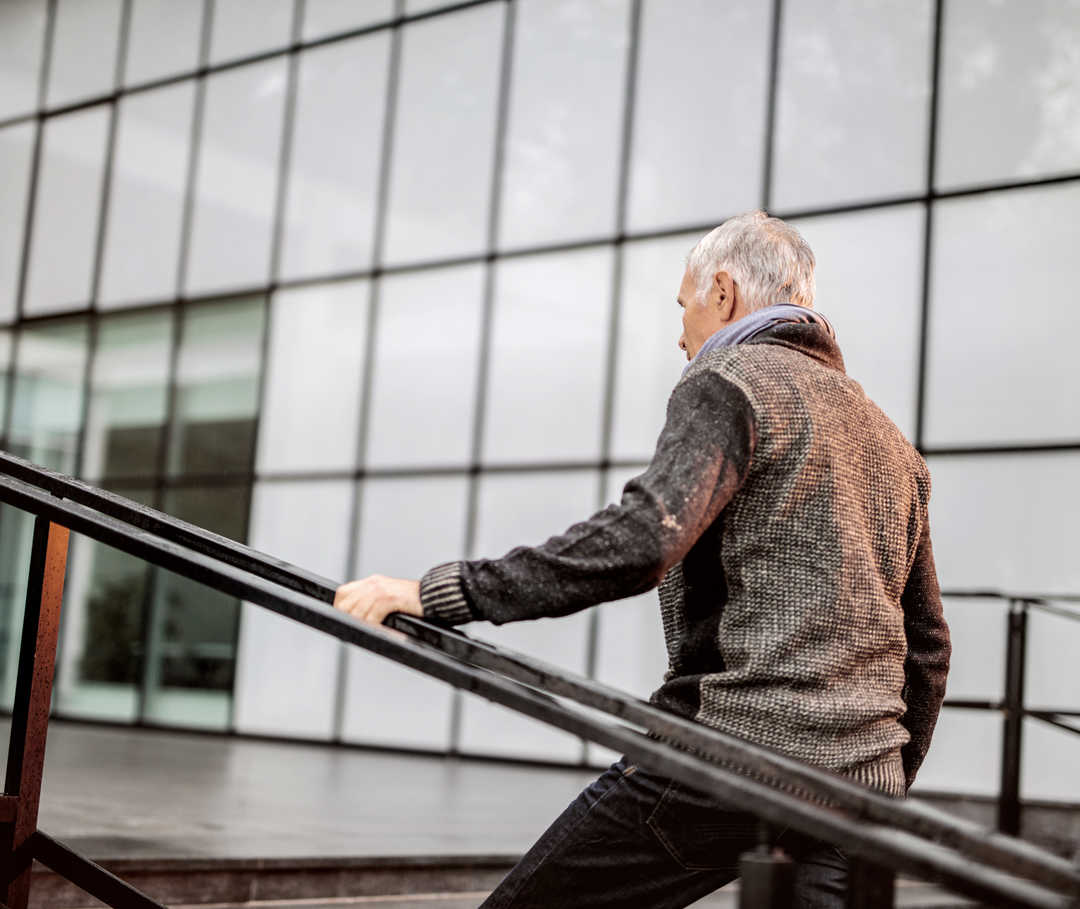 Mann ist vom Treppengehen schnell erschöpft. Herzinsuffizienz-Stadien geben Auskunft über körperlichen Leistungszustand.