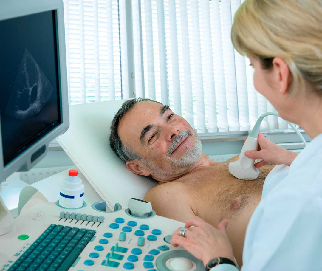 Die Echokardiographie ist eine von vielen Herzuntersuchungen. Herzuntersuchung: Ärztin führt bei Mann Herz-Ultraschall zur Herzdiagnostik durch.