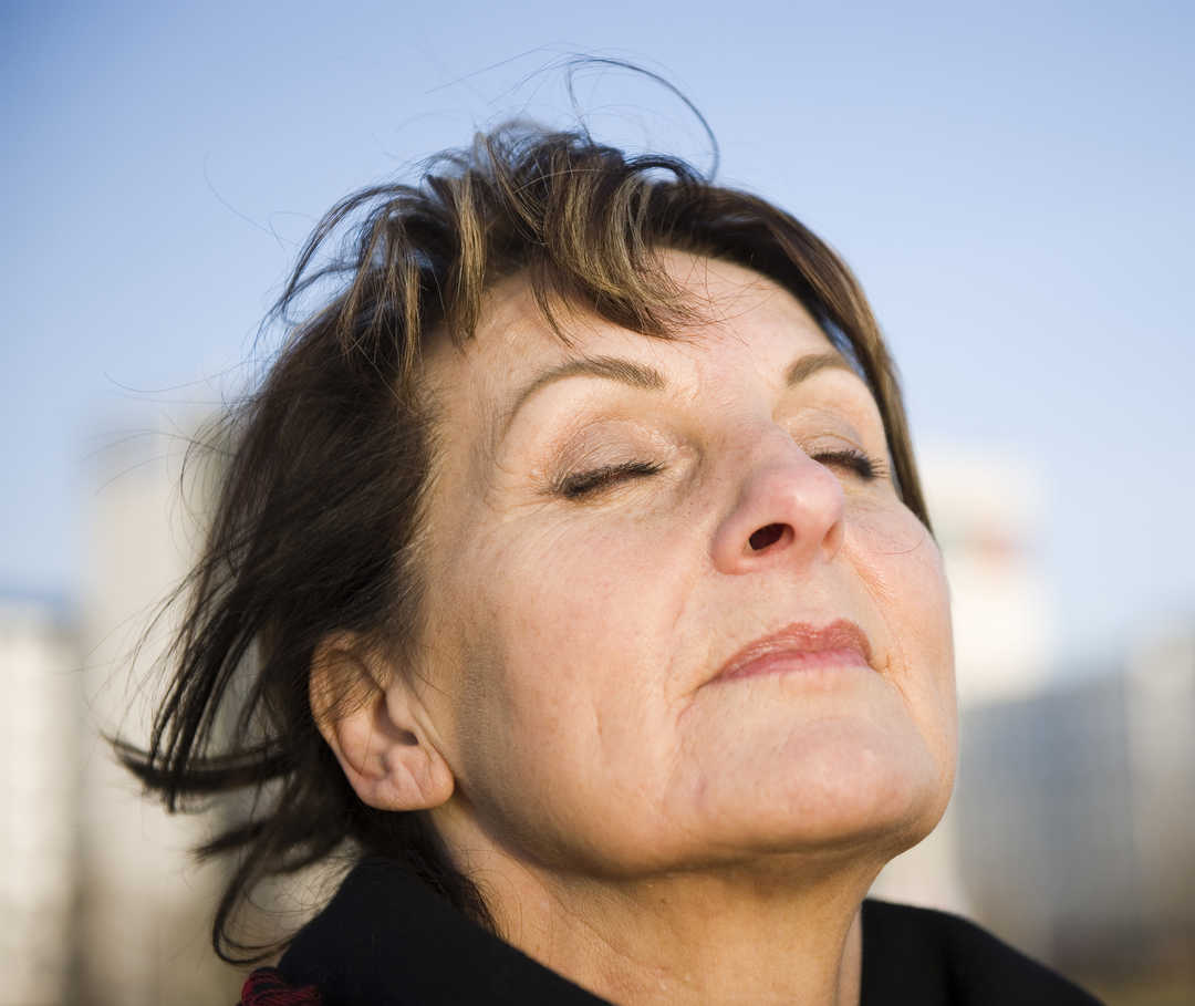 Eine Frau neigt den Kopf leicht nach hinten und schließt die Augen.