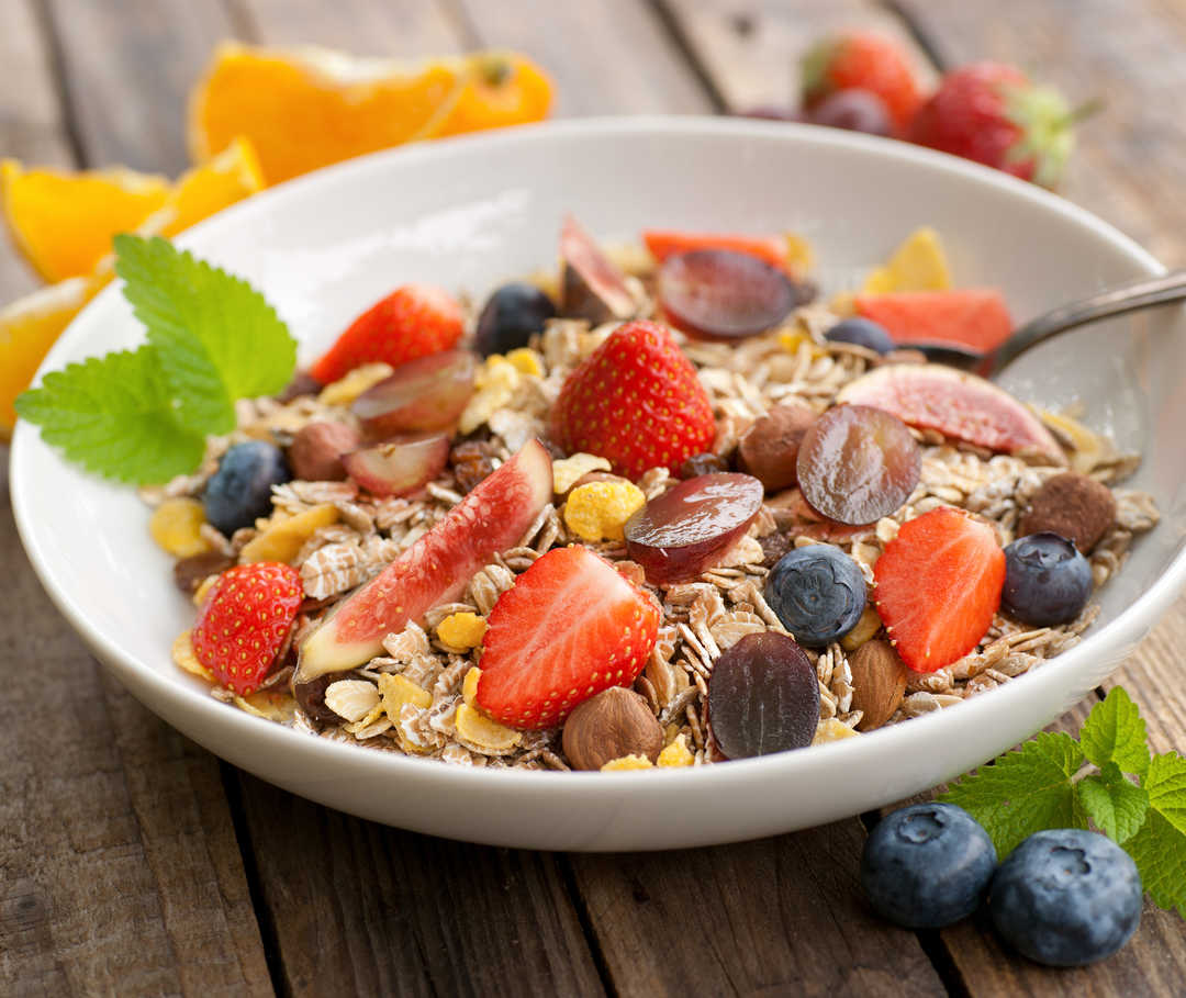 Die Ernährung hat Einfluss auf den Verlauf der Herzschwäche. Ernährung bei Herzinsuffizienz: Teller mit Müsli und frischem Obst