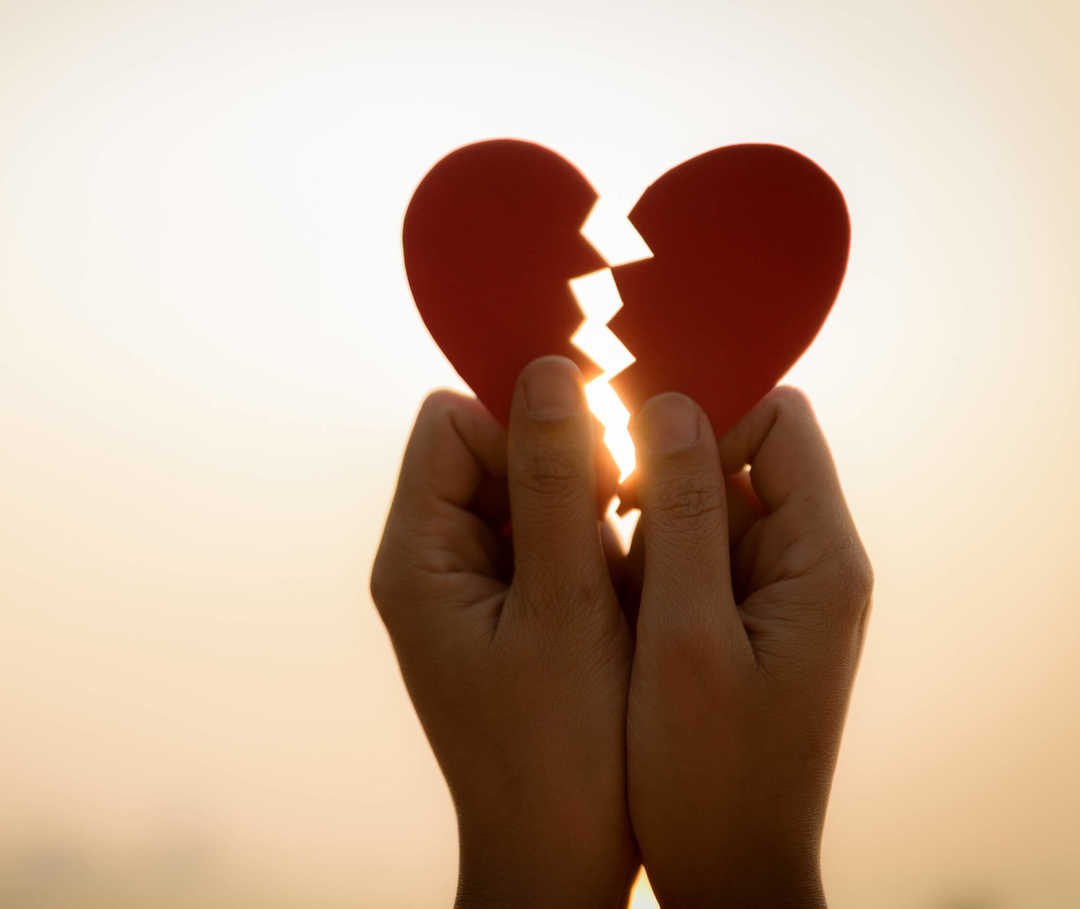 Broken-Heart-Syndrom: zwei Herzhälften aus Papier im Gegenlicht.