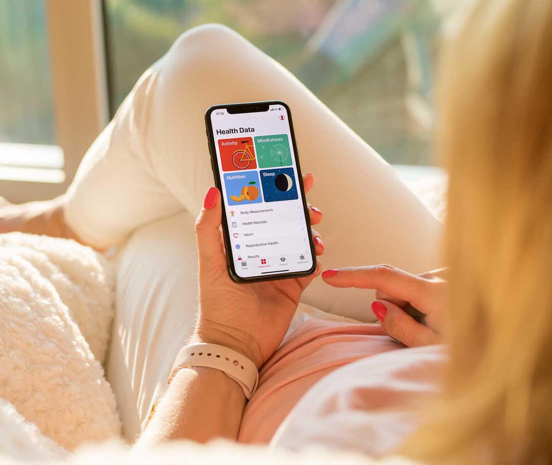 Frau interpretiert die Ergebnisse ihrer Herzratenvariabilitäts-Messung am Handy.