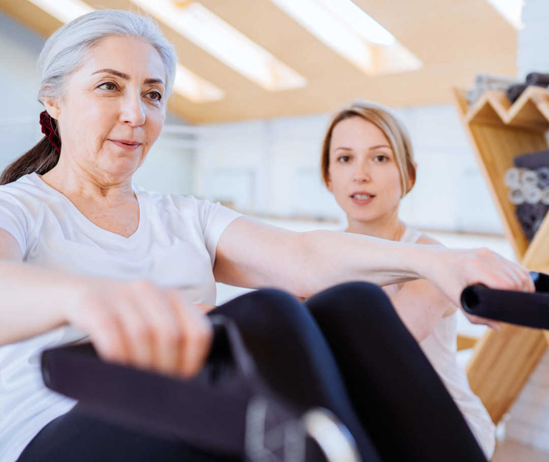 Frau trainiert am Rudergerät – in der Reha nach einer Herz-OP erfolgt ein moderates Sportprogramm.