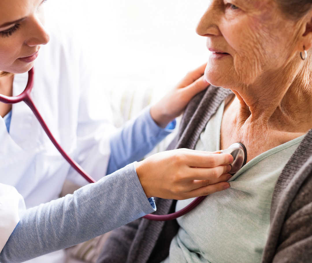 Ärztin hört das Herz einer Patientin mit kardiovaskulärer Erkrankung ab.