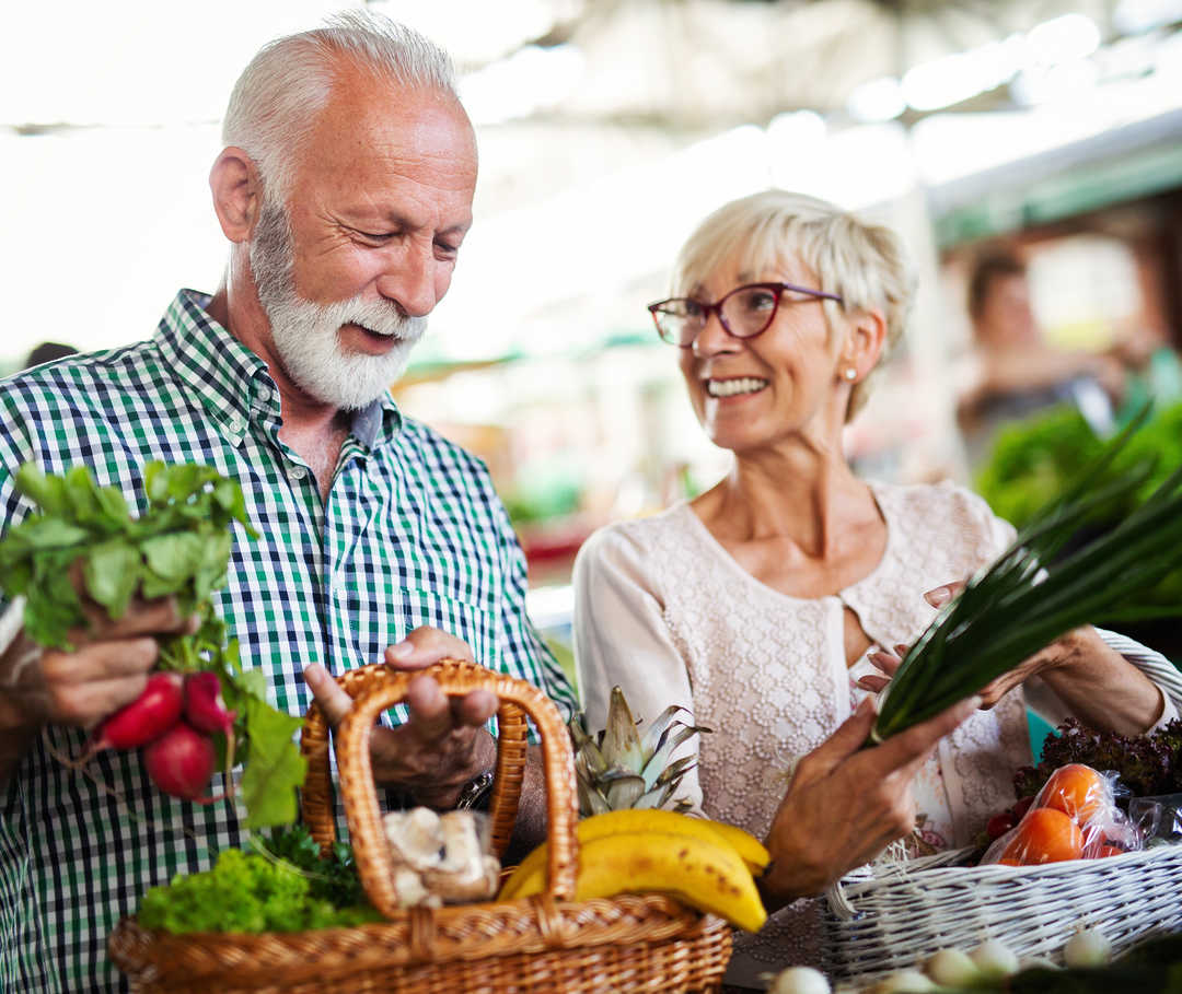Obst und Gemüse enthalten sehr wenig Cholesterin. Älteres Paar mit Hypercholesterinämie mit Einkaufskörben voller frischem Gemüse.
