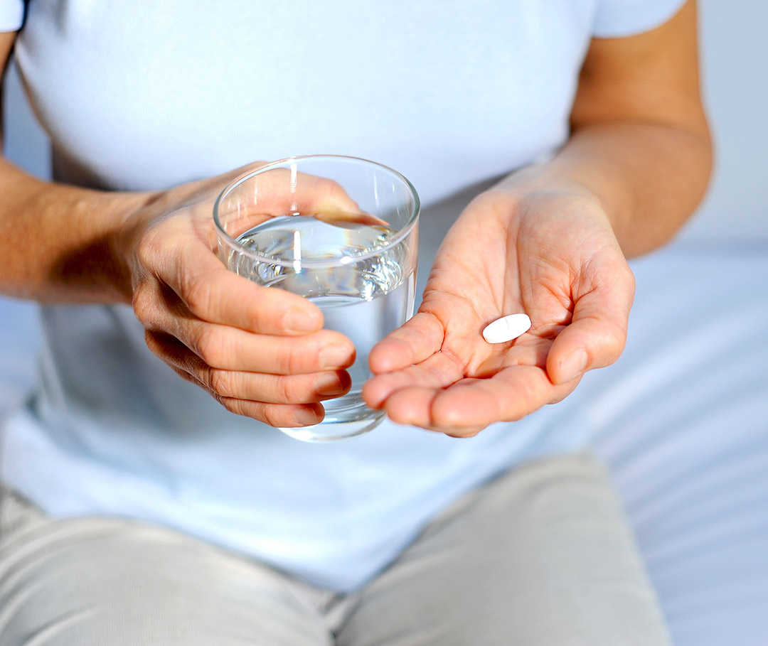 Frau hält eine Tablette in der Hand, die bei der Behandlung ihrer Anämie helfen soll.