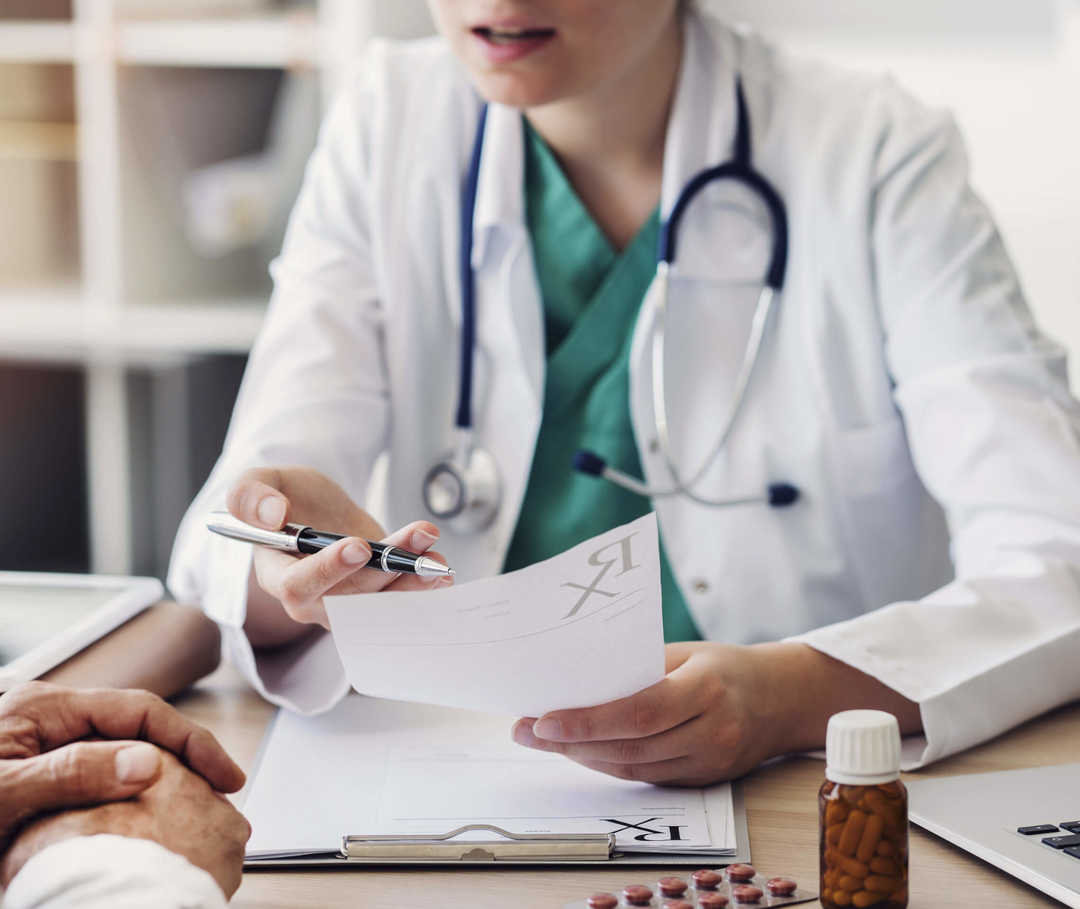 Ärztin sitzt mit einem Patienten an einem Tisch und klärt über die Behandlung mit ARNI auf.
