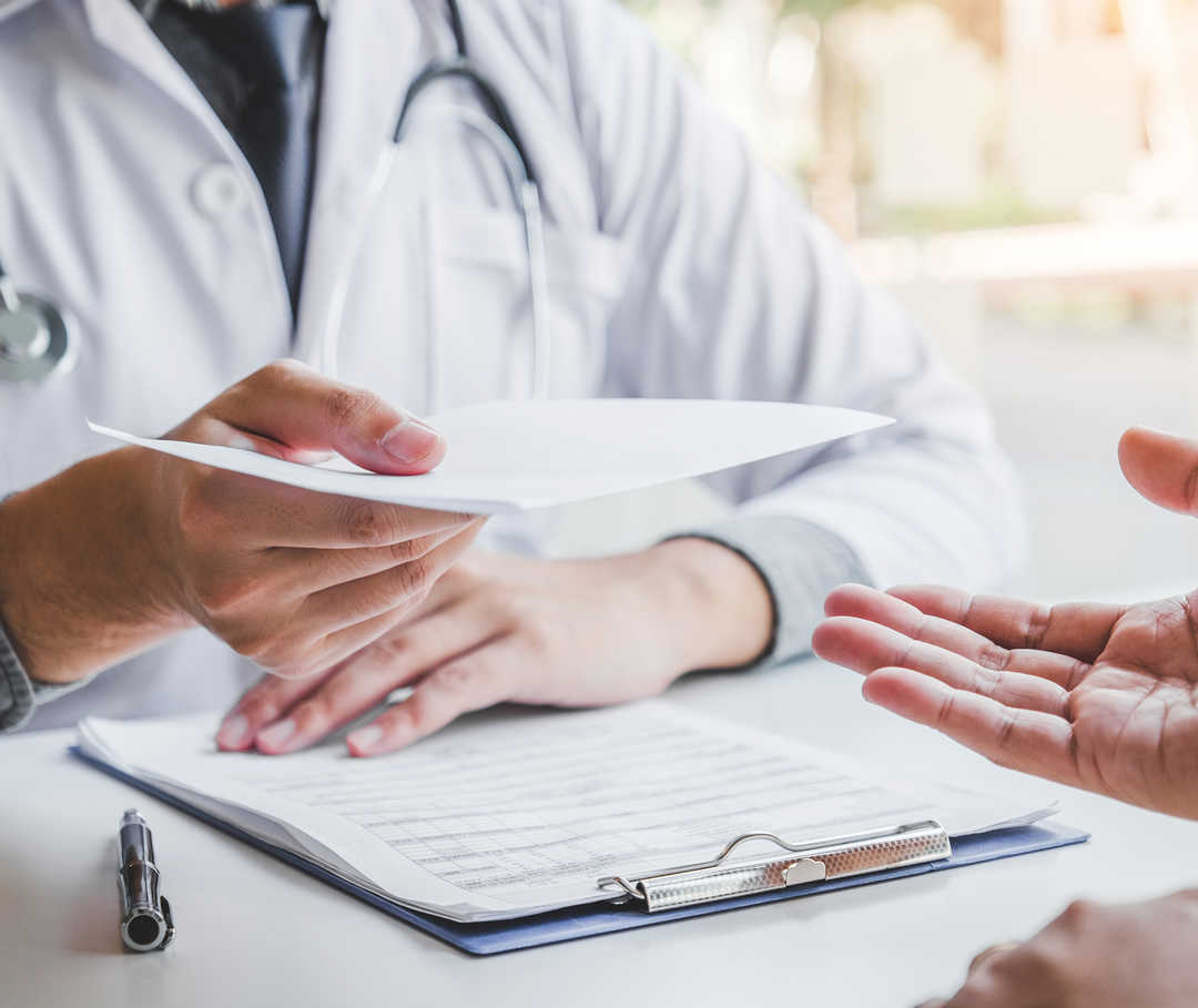 Arzt überreicht Herzinsuffizienz-Patient ein Rezept für einen SGLT2-Inhibitor.