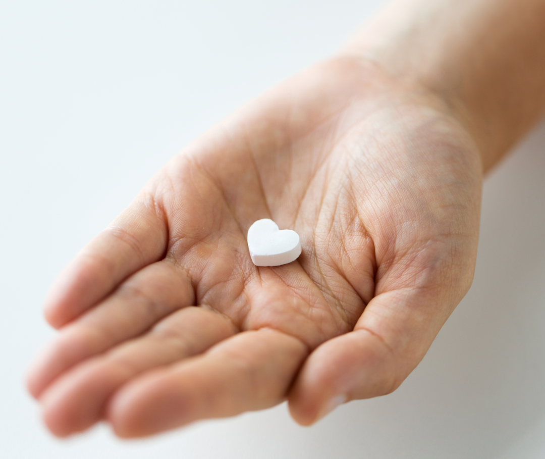 Auf einer geöffneten Handfläche liegt eine MRA-Tablette in Herzform.
