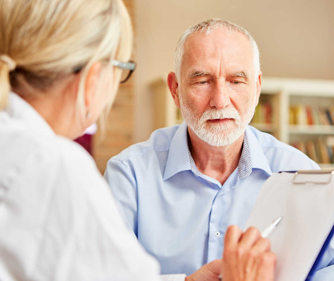 Bei einer Herzinsuffizienz können SGLT2-Inhibitoren zum Einsatz kommen. Ärztin spricht mit Patient über die Einnahme von SGLT2-Inhibitoren bei Herzinsuffizienz.