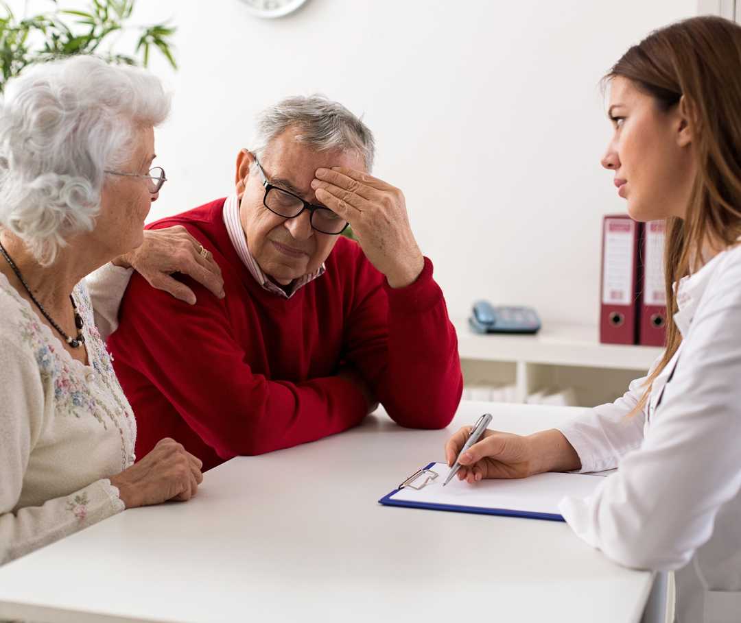 Eine Psychokardiologin klärt ihren Patienten und dessen Frau über funktionelle Herzbeschwerden auf.