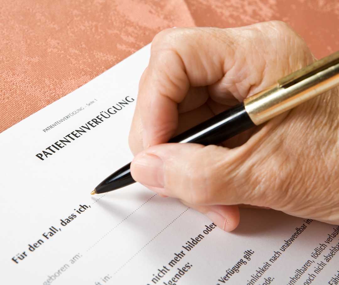 Eine Patientenverfügung klärt gesetzliche Zuständigkeiten. Ältere Frau füllt handschriftlich eine Patientenverfügung aus.